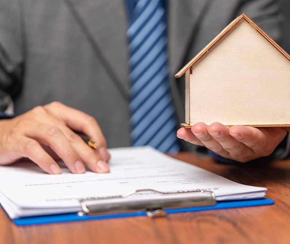 Man in suit holding wooden house