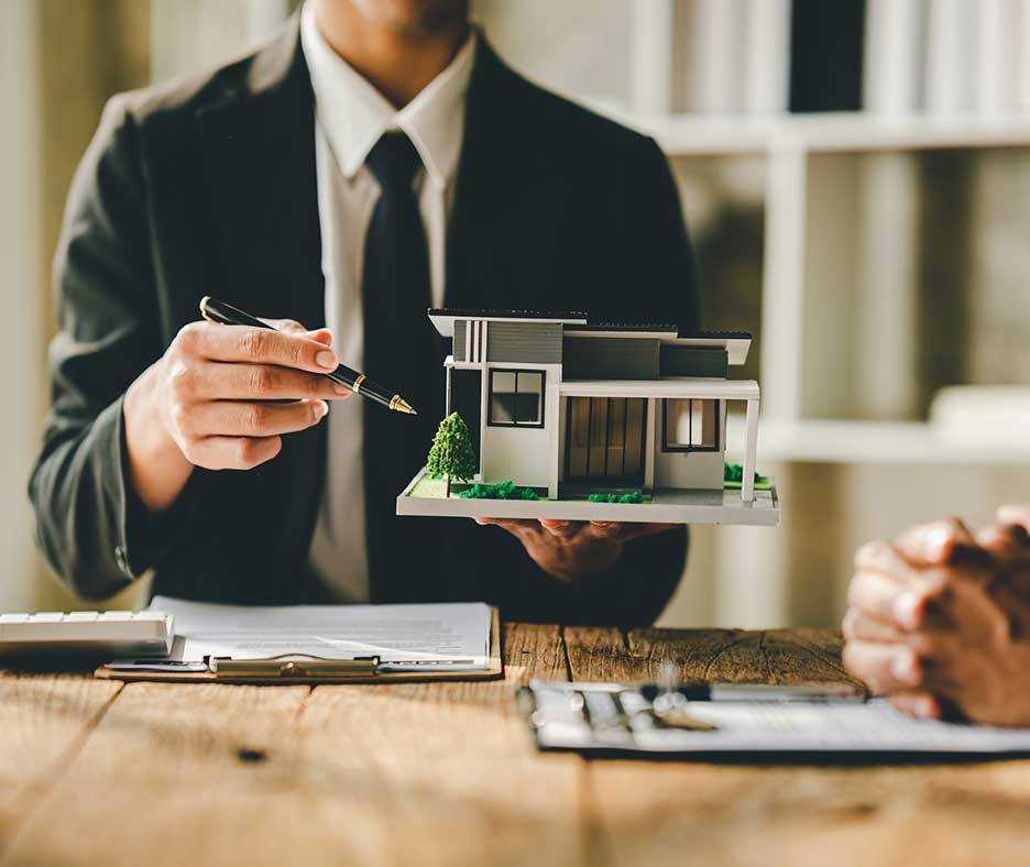 Man in suit holding model house